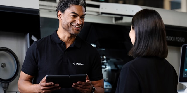 A man and a woman talking in front of a CNC machine