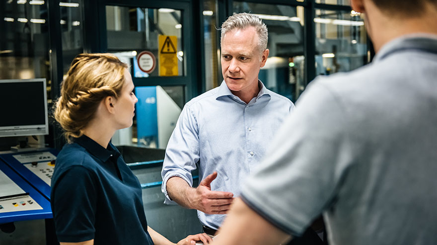 A woman and two men talking to each other in a production environment.